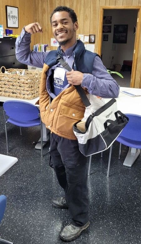 a man in work gear holding a duffel bag