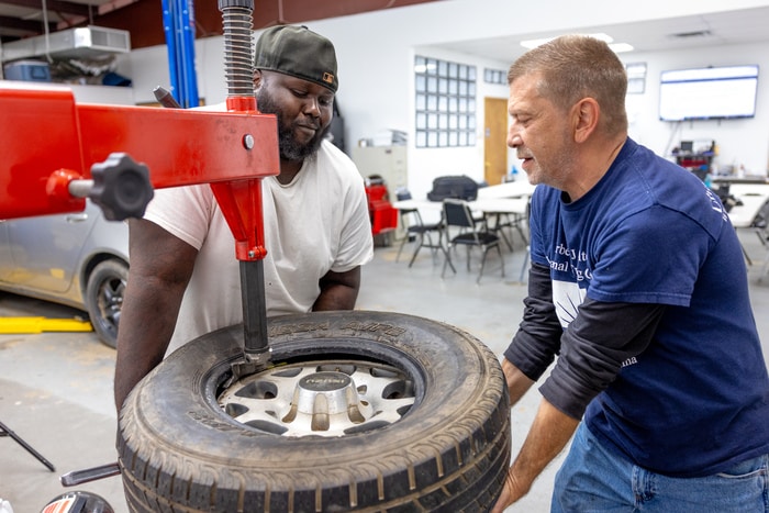 men holding a tire during automotive repairing training classes