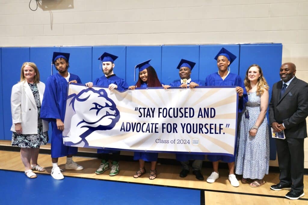 students in blue robes with their diplomas at graduation