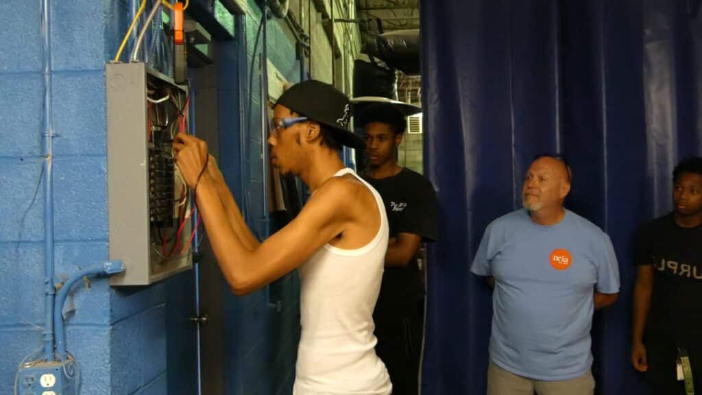 HVAC student fixing a wall panel